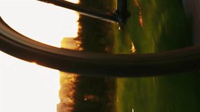 Gear system of bicycle and bike wheel rotation, close up. Vertical video. Female cyclist riding bicycle at sunset. Woman athlete cycling on bike outdoors. Cardio exercises. Active healthy lifestyle