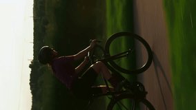 Cyclist hard pushing pedal on road bicycle, doing intense cardio exercises. Vertical video. Female athlete doing cycling interval training on bicycle. Sport activity. Healthy lifestyle.Fitness workout