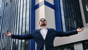 Fashion business man celebrate win victory triumph financial success with raising hands downtown office outdoor. Trendy male boss employee manager enjoy deal profit career opportunity city building