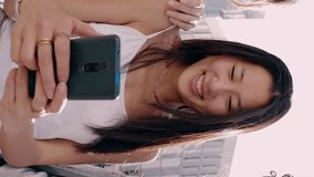 Three multiethnic young women having fun using social media app on mobile phone. Small group of female friends smile while looking at smartphone screen over city background. Vertical video. - Powered by Shutterstock - Get 15% off with code: PIKWIZARD15