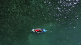 Girl floats on a sup board on a very beautiful sea. Top view of a young girl on a board with a paddle. Surfing activity. Indonesia, Gili Air. Video by drone 4K.