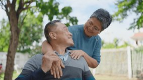 Happy asian elderly married couple relaxing in park together. Cheerful asian adult male patient sitting on wheelchair and senior wife enjoying leisure. Relationship concept - Powered by Shutterstock - Get 15% off with code: PIKWIZARD15
