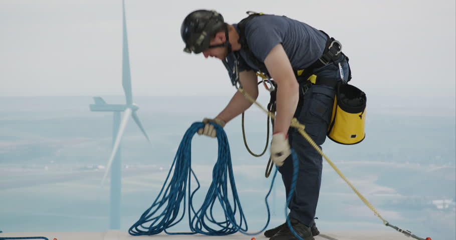 Engineer performing repairing and maintenance works on top of wind turbine nacelle house. Portrait of skilled professional worker working at high altitude 