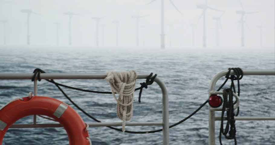 Maintenance engineer checking the data on tablet, approaching offshore wind turbine farm on a service vessel. Portrait of skilled professional preparing to work at high altitude Royalty-Free Stock Footage #1105814005