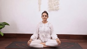 Video of beautiful woman in white outfit performing Seated Side Bend Pose exercise.
