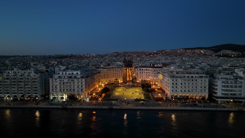 drone aerial night video of harbor city of thessaloniki greece with cars passing and lights during sunset in 4k high quality