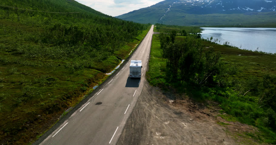 Aerial view following a motorhome on a mountainous road, in sunny northern Norway