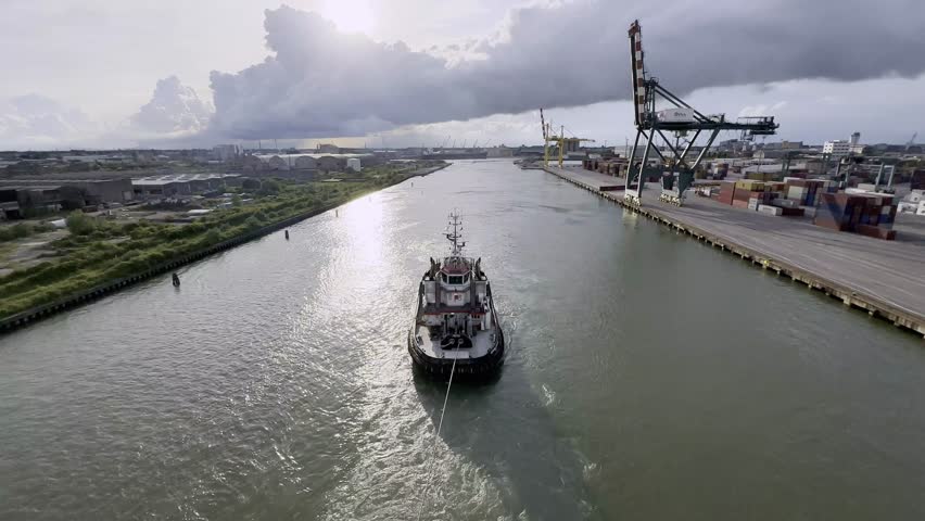 A tugboat helps the cruise ship sail away from the port of Venice. A rope is stretched between the tug and the big ship. Sunset