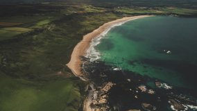 Sun, Northern Ireland, White Beach, Atlantic Ocean - aerial view coast beach. People walking on sand white shore with tranquil coastal wavy water. Cloudy summer scenery. Footage shot