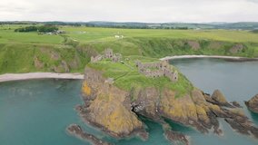Aerial drone video of the castle ruins of Dunnottar near Stonehaven in Aberdeenshire, Scotland. The ruins can be found at the coastline with beautiful green cliffs.