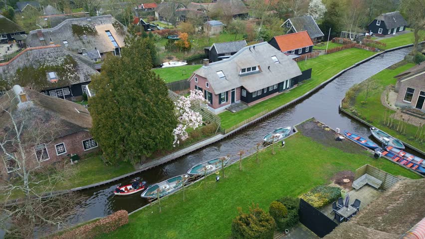 Giethoorn village - Venice of the Netherlands. Flying around canal. Boat is passing by Royalty-Free Stock Footage #1105826599