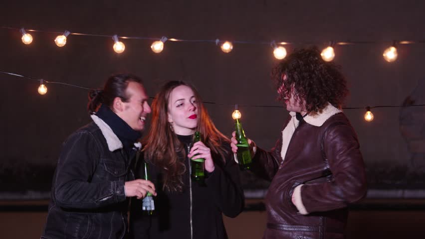Slow motion on young woman with her friends on the terrace on the evening drinking beer talking happily | Shutterstock HD Video #1105826801