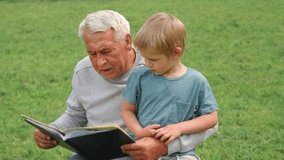 Happy grandfather reading book to curious grandson outdoors. Close up. Grandpa with grandchild spending time together. Family time comes in various forms. 4s year boy and senior man read story in park - Powered by Shutterstock - Get 15% off with code: PIKWIZARD15