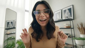 Webcam view adorable funny freelancer entrepreneur making silly faces and hand gestures working remotely 4K. Super cute excited hispanic woman in eye glasses talking to camera by conference video call