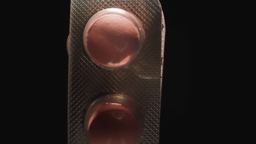 Curved silver blister with pink pills on black background. Effective painkillers prescribed by doctor from headache symptoms. Pharmacy concept macro