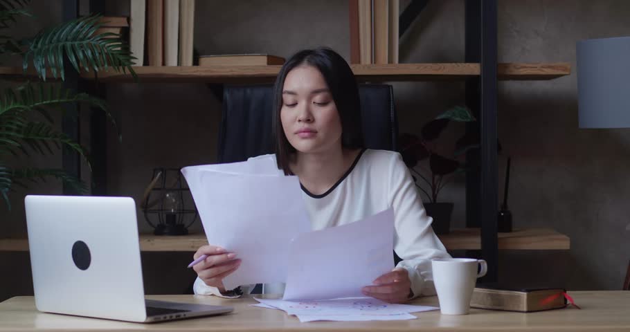 Asian businesswoman checking corporate documents sitting at desk in office feeling bored female reads documents, analyzes and feeling bored female prepares audit report workplace while feeling bored Royalty-Free Stock Footage #1105842633