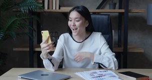 Pretty asian woman sit on chair holding smartphone have virtual meeting enjoy personal chat with friend. young asian woman have virtual meeting, event, modern wireless tech, concept virtual meeting