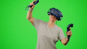 The woman wearing VR headset dancing in virtual reality.The girl on chroma key green screen background in virtual reality dancing in game.Concept dance in virtual reality VR headset, leisure activity