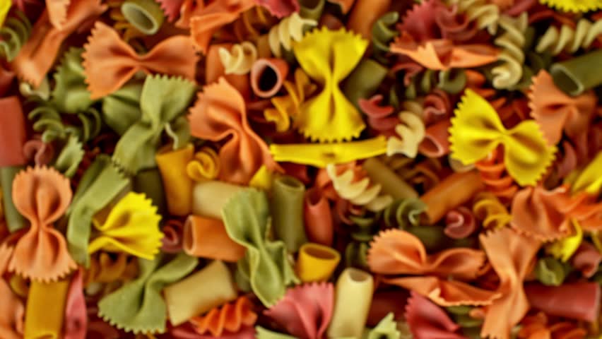 Super slow motion of flying uncooked Italian pasta mix on black background. Filmed on high speed cinema camera, 1000 fps, placed on high speed cine bot, following the object. Speed ramp effect.