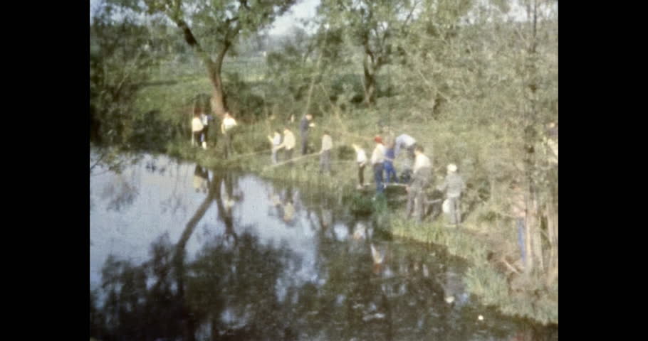 Fishermen fishing lake on green park background. People holding fishing rods, catch fish in river. Summer hobby leisure in nature. Recreation in vacation. Archival vintage color film. Archive travel