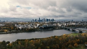 The drone flies backwords away from the city centre of Warsaw across the river on a cloudy fall day in Poland Aerial Drone Footage 4k
