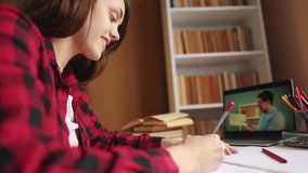 distance learning online education school. girl student studying at home on laptop watching an online seminar near a bookcase desk online. distance education concept. teen girl exam on an online