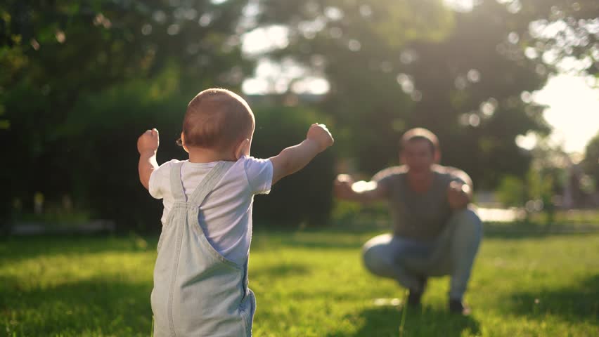 baby first steps. happy family kid dream concept. baby son goes to his father in the park learns to walk first steps. baby first steps in nature. father teaches son to walk lifestyle Royalty-Free Stock Footage #1105853339