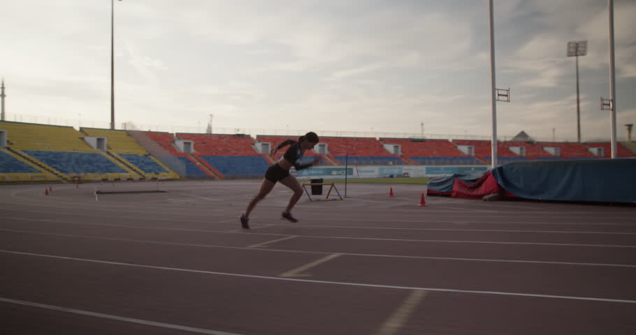 Sportive woman running on track during workout in early morning