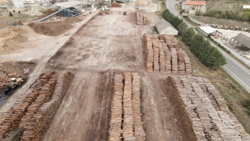 Aerial view of operating wood factory at rural area with tractors circulating in 