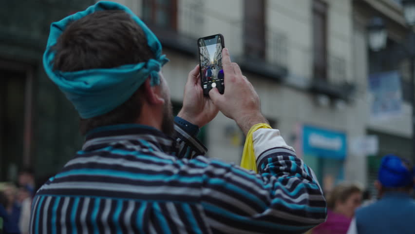 Caucasian boy with blue scarf in his hair taking a photo with his mobile phone