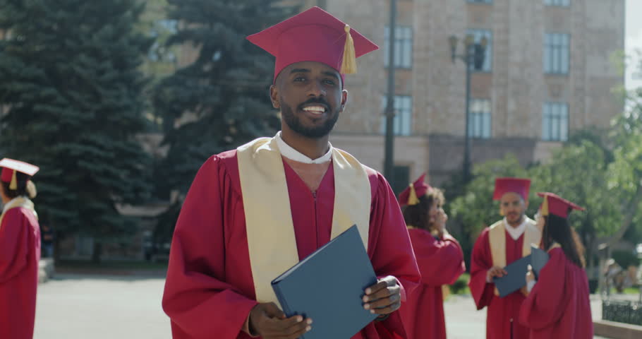 Slow motion portrait of confident African American man student standing in graduation mortar board holding diploma. Higher education and ambitious youth concept. Royalty-Free Stock Footage #1105870859