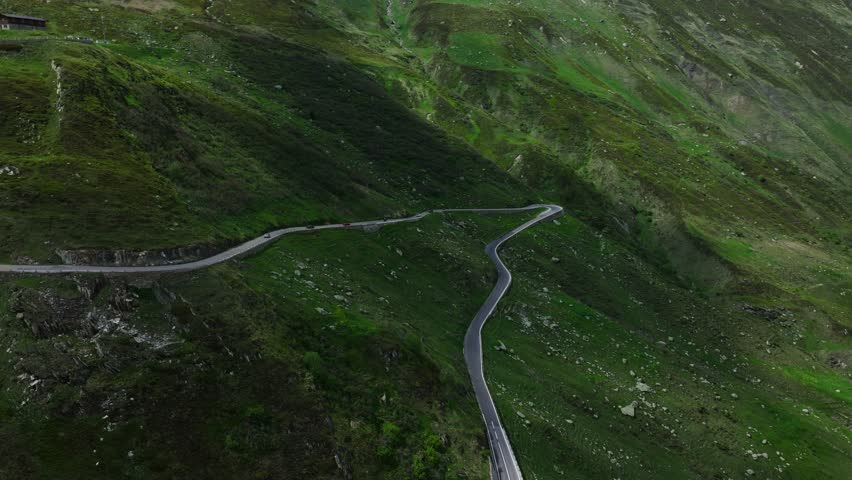 Cars driving along Furka Pass winding road in Switzerland. Aerial drone scenic view