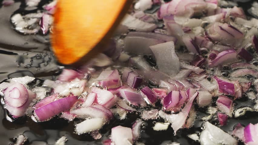 Red onion is fried in oil in a pan and mixed with a spatula. Medium plan