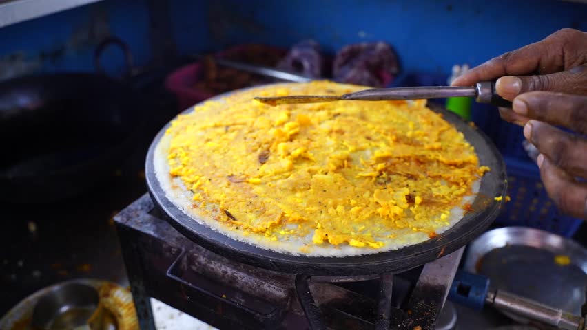Spreading hot chili and other spices with potato stuff on famous Indian food dosa while making dosa on a hot gas stove, slow motion stock footage