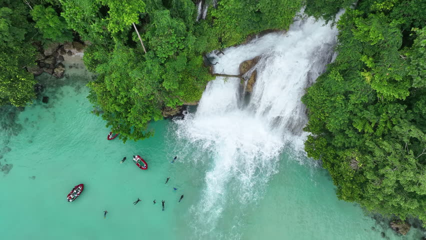 The scenic Momon waterfall flows from the primordial rainforest of West Papua into the shallow sea. This spectacular waterfall is found about a day
