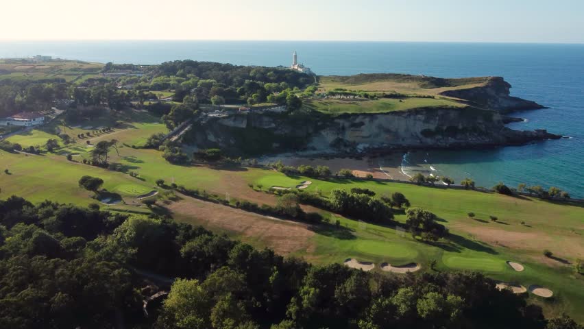 Aerial view of golf courses on the outskirts of Santander city. Beautiful sunset colours. In the center is Playa de Mataleñas, an beautiful small beach. In background Lighthouse Cabo Mayor. Descending