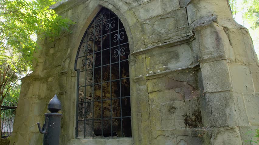A man takes off his straw hat and looks at an old gothic building. Crypt