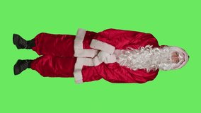 Man dressed as santa feeling impatient, waiting for something while he stands over full body greenscreen backdrop. Saint nick character pacing around the studio, christmas eve holiday.