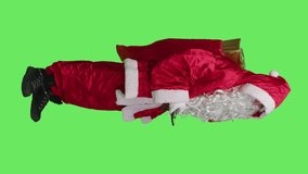 Vertical video Side view of modern santa claus answers phone call in studio with full body greenscreen, talking on remote chat using smartphone. Father christmas carries sack of presents and toys for