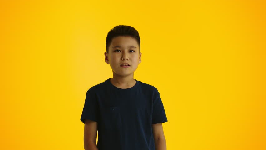 Young boy thinking stroking his chin with a hand on a yellow background. Concept of searching for interesting and useful activities for children Royalty-Free Stock Footage #1105904589
