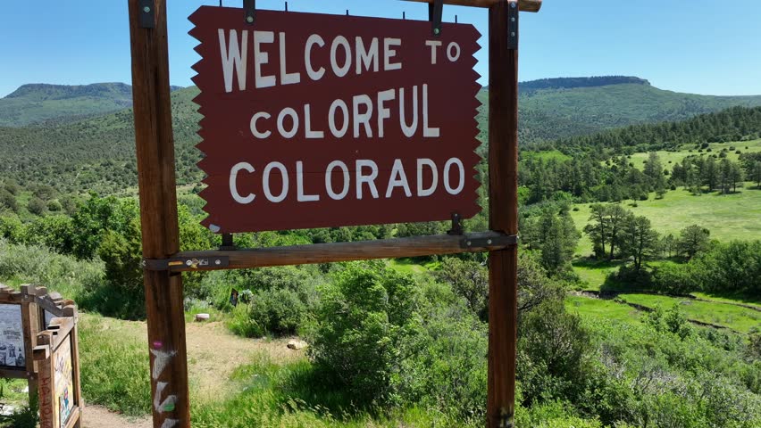 Welcome to Colorful Colorado sign along interstate highway with beautiful scenic lookout. Aerial rising shot revealing scenic mountains in CO. Royalty-Free Stock Footage #1105908117