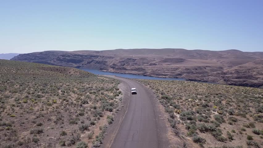 Van drives through scablands sagebrush by Columbia River, aerial view