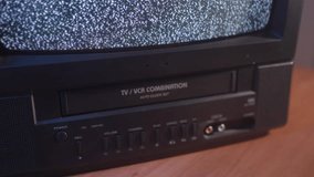 Inserting a VHS tape in a TV VCR to watch an old vintage movie.