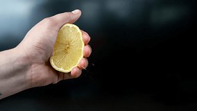 Male hand squeezing a half of lemon fruit. Juice bursting out on camera on slow motion on black background isolated. Healthy organic food lifestyle. Vitamin C - Powered by Shutterstock - Get 15% off with code: PIKWIZARD15