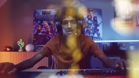 Male gamer in headphones plays shooter on computer in modern apartment. View from PC screen perspective with animated online video game. Gaming at home, cybersport. Futuristic VFX animation. Zoom out.