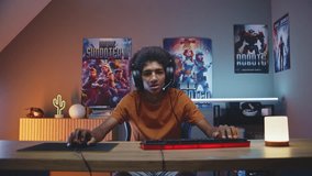 Excited teenage gamer in headphones plays online video game on computer in neon room. African American guy enjoys multiplayer cybersport championship. Gaming at home. POV from PC screen perspective. - Powered by Shutterstock - Get 15% off with code: PIKWIZARD15