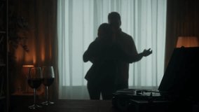 Vintage record player with a rotating vinyl record and glasses with red wine on the table close up. A couple is dancing a slow dance while enjoying a pleasant evening together. Silhouette. Slow motion - Powered by Shutterstock - Get 15% off with code: PIKWIZARD15