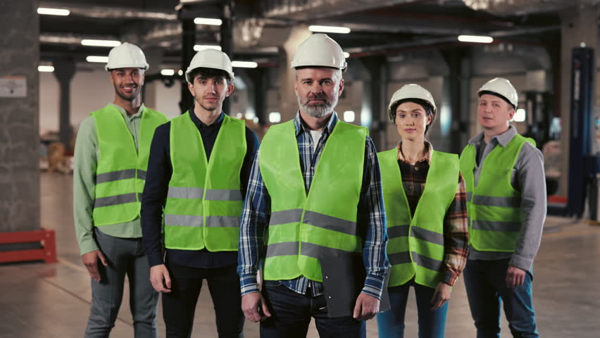 A Group of Warehouse Workers Stands in a Large Distribution Center with their Arms Crossed. Portrait of the Workers. People Looking at the Camera with Smile. Logistic. Distribution Royalty-Free Stock Footage #1105918837
