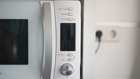 Front video of a hand placing a cup to heat in the microwave, pressing the operation button twice to start heating.	