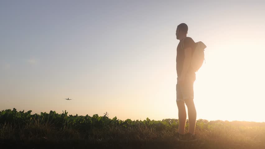Man with backpack looking up to airplane landing at airport during beautiful summer sunset. Real time in 4K resolution.
 Royalty-Free Stock Footage #1105930055